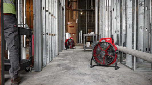 Milwaukee M18 Brushless red jobsite fan in a narrow corridor between metal frames, demonstrating its slim profile and portability in tight spaces