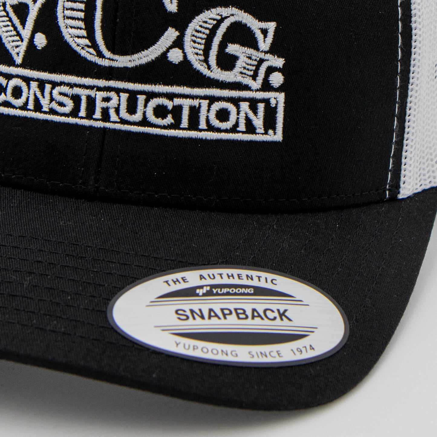 Close-up of VCG Construction logo on black and white snapback hat