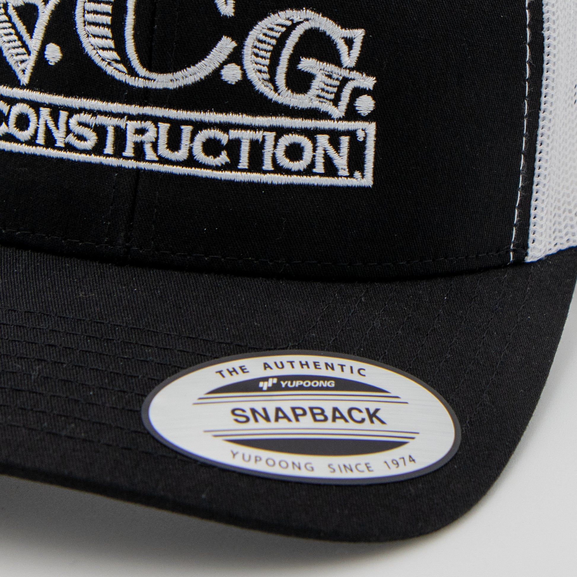 Close-up of VCG Construction logo on black and white snapback hat