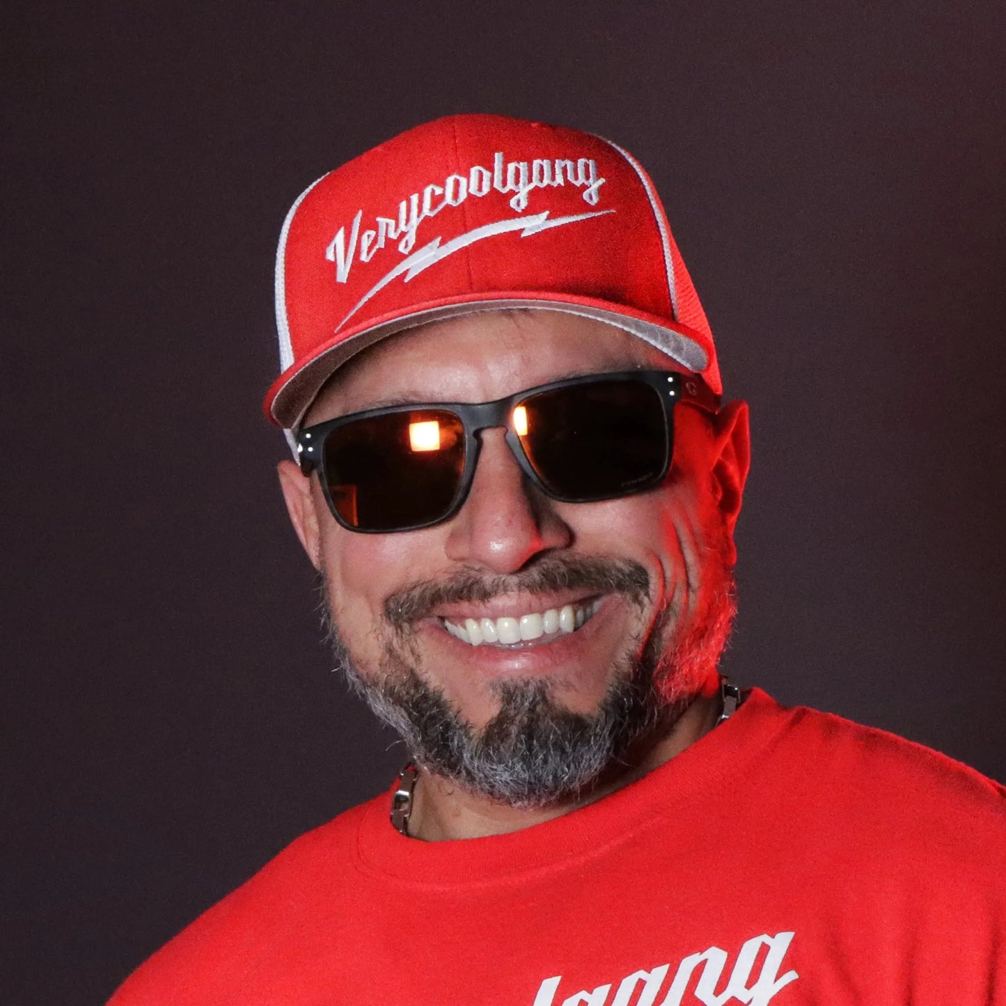 Experience the sleek appeal of our VERYCOOLGANG Thunderbolt logo, intricately embroidered in white on our two-tone Red and White Flexfit Trucker Mesh Cap.