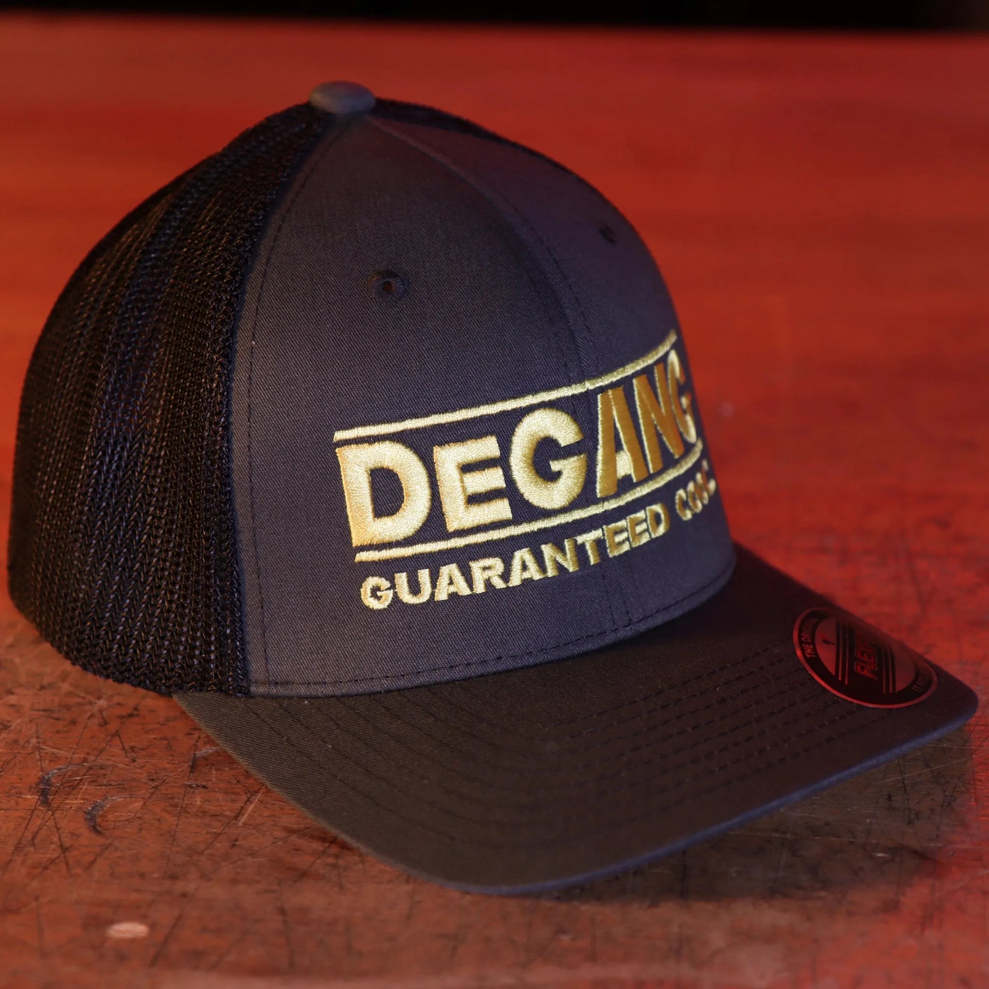 DeGANG GUARANTEED COOL in yellow gold color on 2 tone grey and black FLEXFIT TRUCKER MESH hat