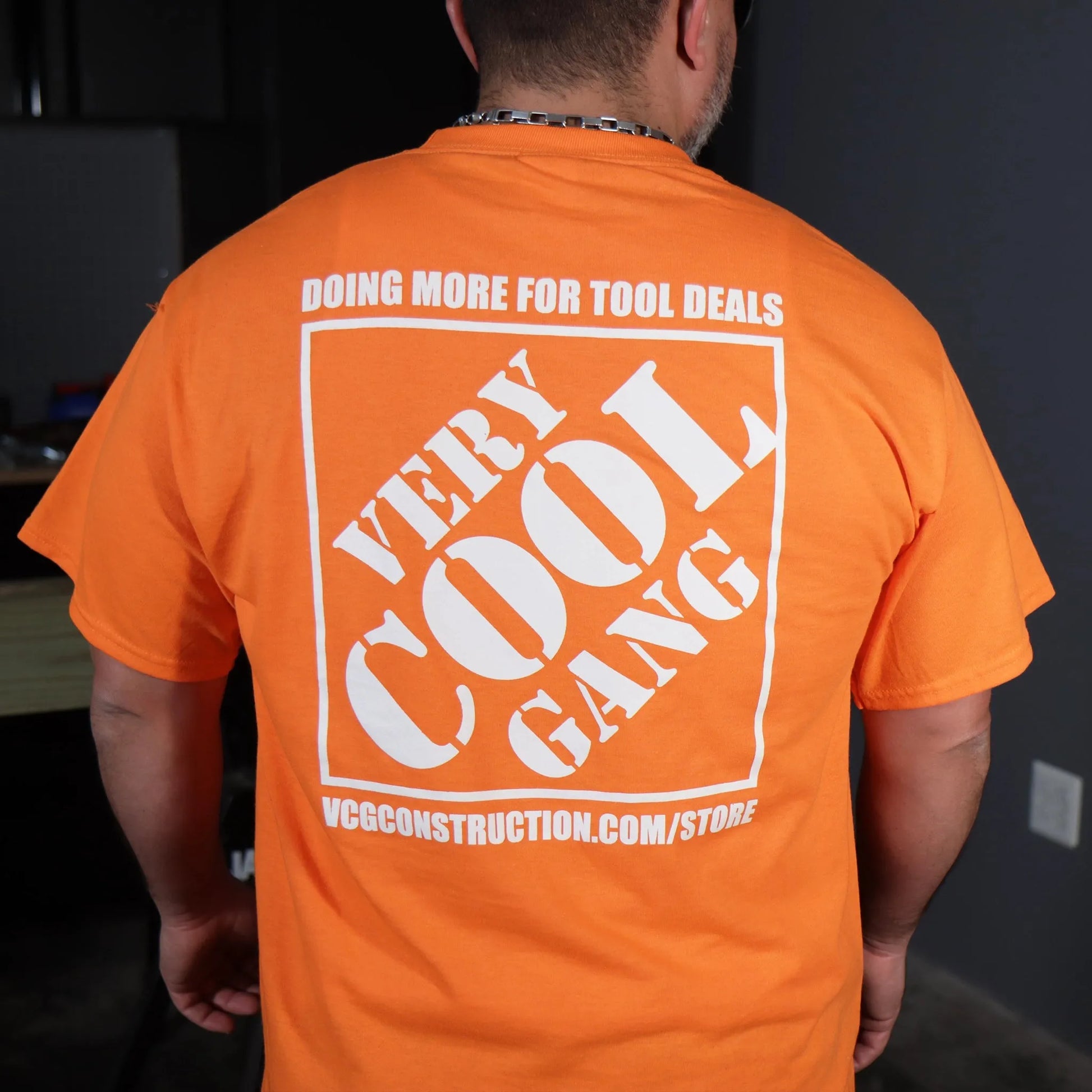Stand out in our High Visibility Orange shirt featuring the striking 'Very Cool Gang Doing More for Tool Deals' logo prominently displayed in white on the back